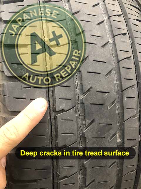 Image shows auto repair mechanic pointing to deep cracks in tire tread surface - A+ Japanese Auto Repair Inc. - San Carlos, CA